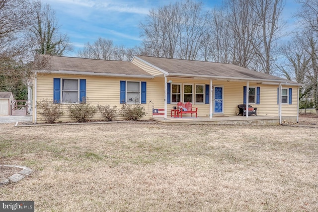 ranch-style house featuring a porch, a front yard, and an outbuilding