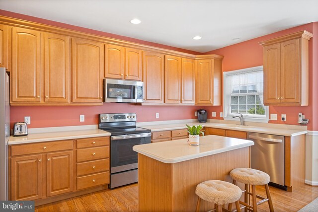 kitchen with stainless steel appliances, a kitchen island, light countertops, and a sink