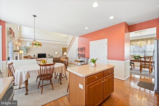 kitchen featuring a center island, light wood-style flooring, baseboards, pendant lighting, and open floor plan