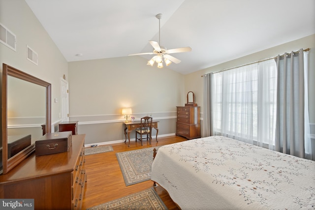 bedroom with baseboards, visible vents, wood finished floors, and lofted ceiling