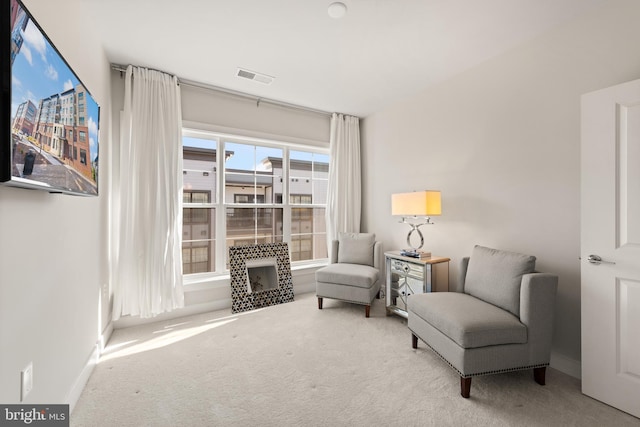 sitting room featuring light colored carpet, visible vents, and baseboards