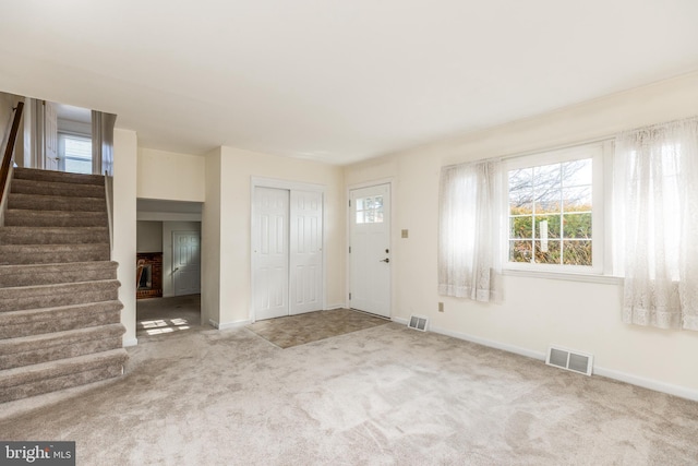 carpeted foyer featuring visible vents, plenty of natural light, and stairway