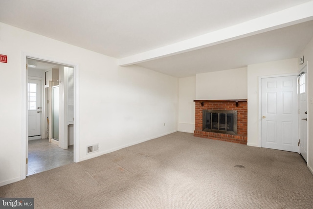 unfurnished living room featuring beam ceiling, visible vents, a fireplace, and carpet flooring