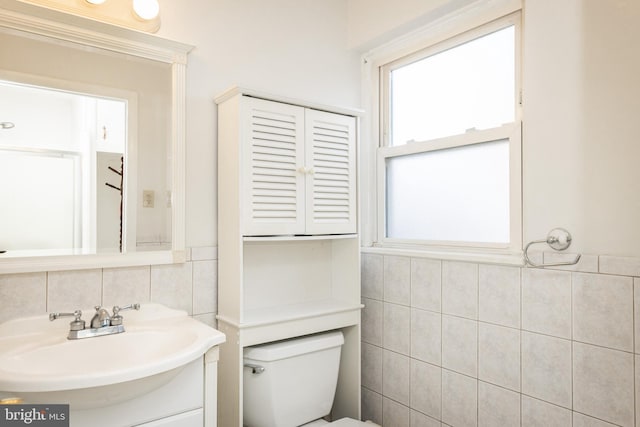 bathroom with tile walls, toilet, and vanity