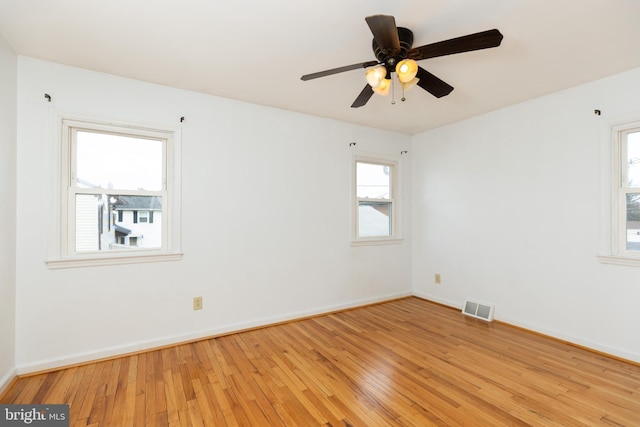 spare room with light wood-style floors, visible vents, baseboards, and a ceiling fan