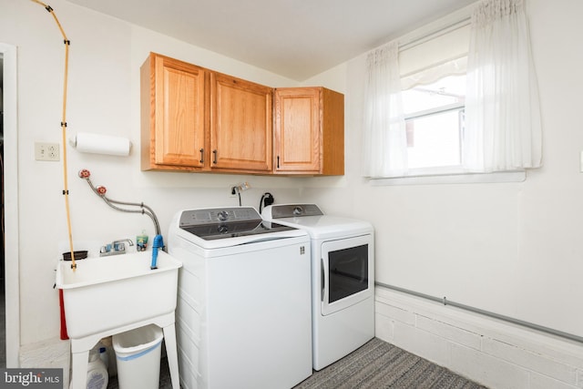 clothes washing area with cabinet space, a sink, and independent washer and dryer