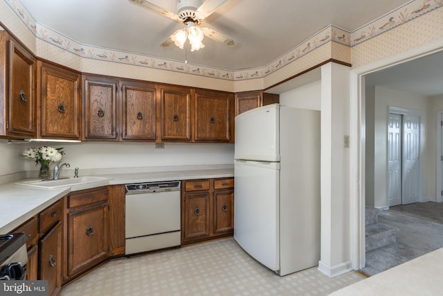 kitchen with white appliances, a sink, light floors, and wallpapered walls