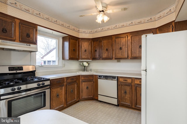 kitchen with under cabinet range hood, white appliances, light countertops, light floors, and wallpapered walls