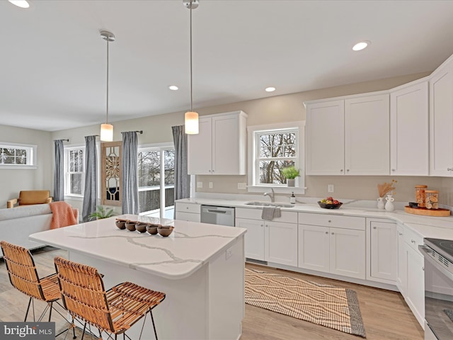 kitchen featuring hanging light fixtures, a breakfast bar area, a sink, and white cabinets