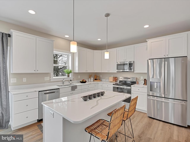 kitchen with stainless steel appliances, a center island, decorative light fixtures, and white cabinets