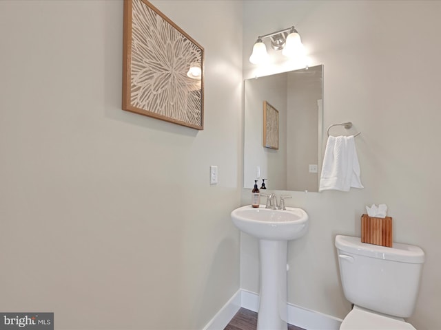 half bath featuring a sink, toilet, and baseboards