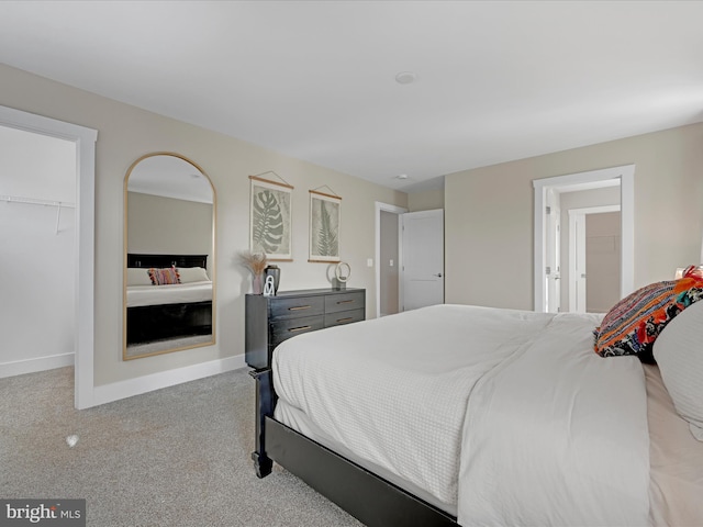 bedroom featuring baseboards, a spacious closet, a closet, and light colored carpet