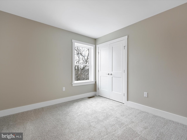 unfurnished bedroom featuring a closet, light carpet, visible vents, and baseboards