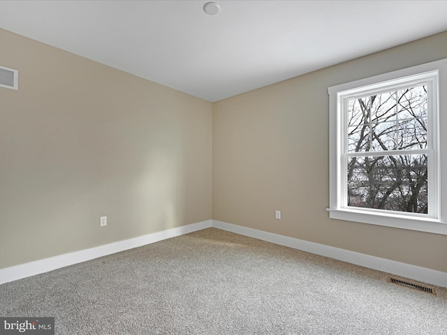 carpeted spare room with baseboards and visible vents