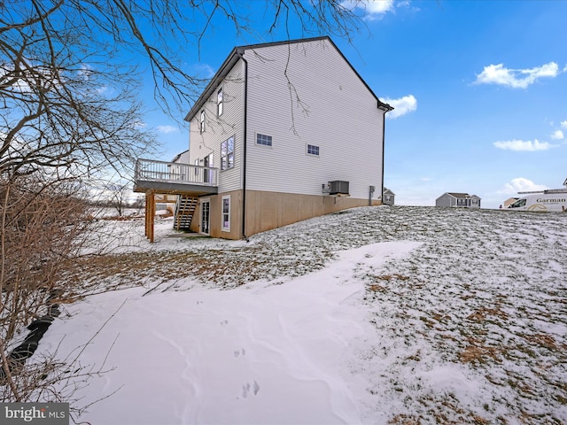 view of snowy exterior featuring stairs, cooling unit, and a wooden deck