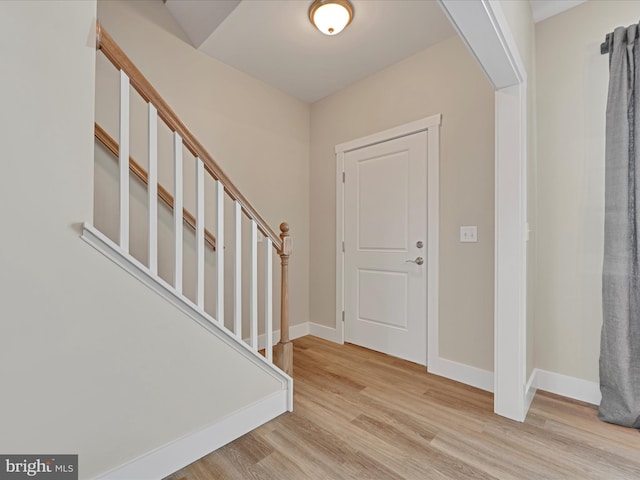 foyer featuring light wood-style floors, stairs, and baseboards