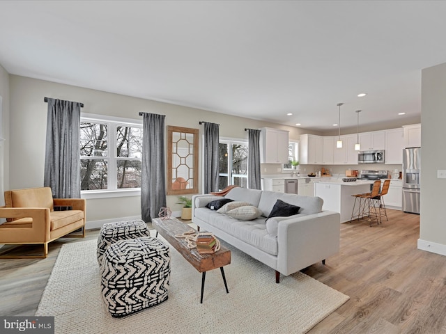 living room with light wood-style floors, baseboards, and recessed lighting