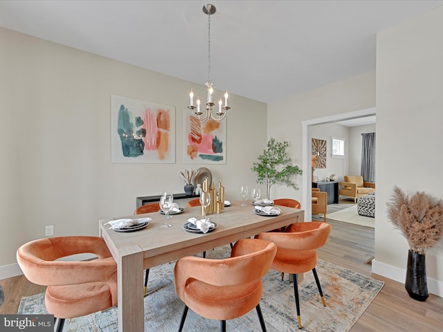 dining area featuring baseboards, a notable chandelier, and light wood finished floors