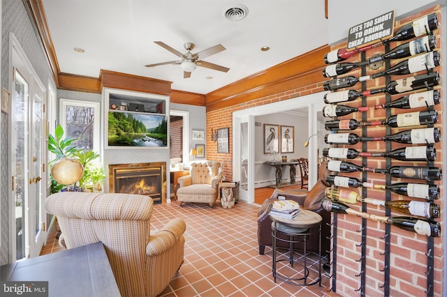 interior space featuring a glass covered fireplace, visible vents, and a ceiling fan