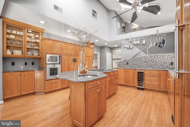 kitchen with a center island with sink, visible vents, wine cooler, stainless steel appliances, and a sink