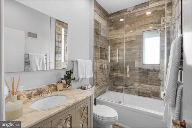 bathroom with visible vents, vanity, toilet, and combined bath / shower with glass door