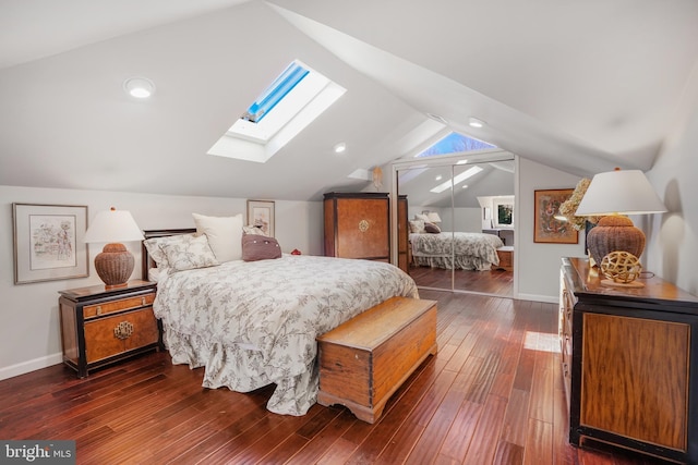 bedroom featuring vaulted ceiling with skylight, baseboards, dark wood finished floors, and a closet