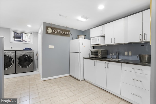 kitchen featuring a toaster, white appliances, a sink, independent washer and dryer, and dark countertops