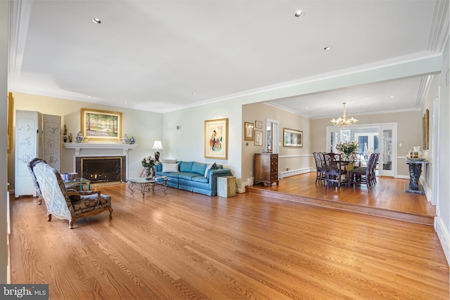 living area featuring light wood finished floors, a warm lit fireplace, baseboard heating, and an inviting chandelier