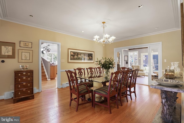 dining space with ornamental molding, light wood-style flooring, and baseboard heating