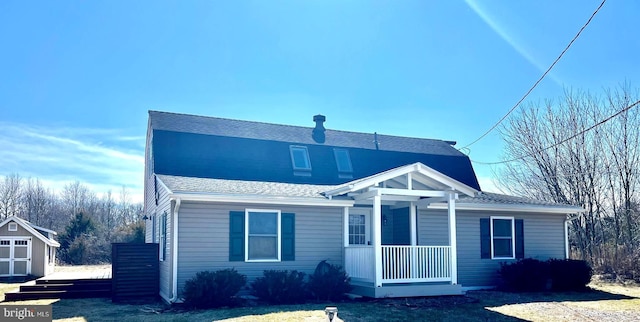 view of front of house featuring an outdoor structure, covered porch, and a shingled roof