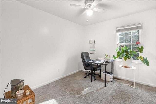 carpeted office space featuring baseboards and a ceiling fan