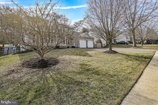 view of front of house with driveway, an attached garage, fence, and a front yard