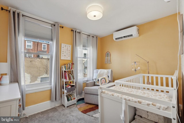 bedroom with a crib, baseboards, light colored carpet, and a wall mounted air conditioner