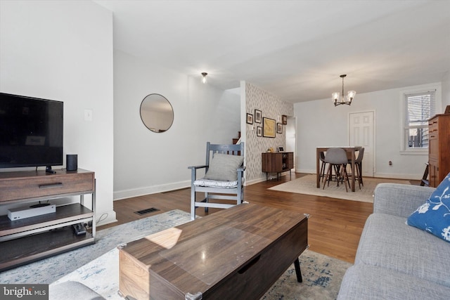 living area with baseboards, visible vents, a chandelier, and wood finished floors