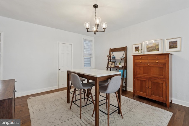 dining area with an inviting chandelier, baseboards, and dark wood-style flooring