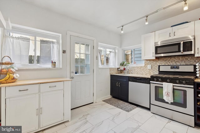 kitchen with decorative backsplash, marble finish floor, stainless steel appliances, light countertops, and a sink