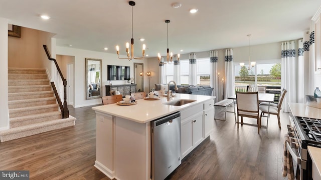 kitchen featuring a center island with sink, light countertops, appliances with stainless steel finishes, open floor plan, and a sink