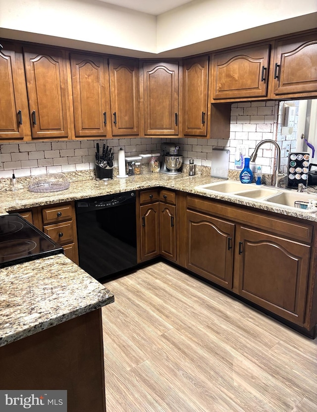 kitchen featuring decorative backsplash, dishwasher, light wood finished floors, and a sink