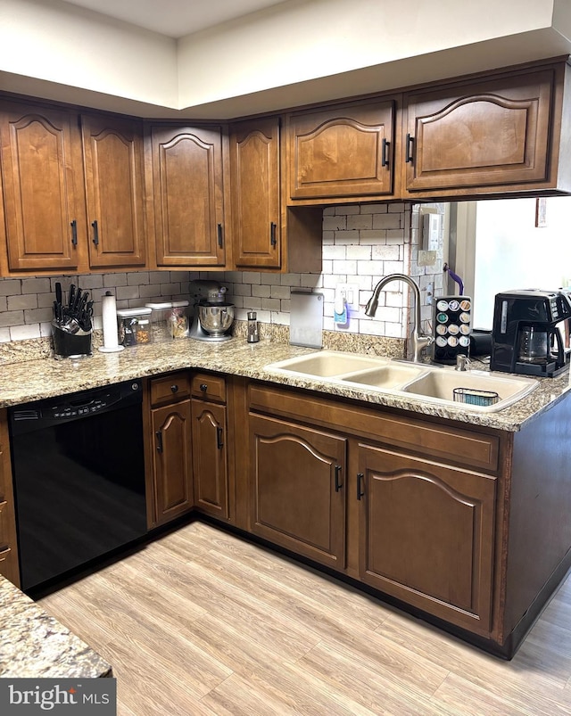 kitchen with black dishwasher, tasteful backsplash, a sink, and light wood-style flooring