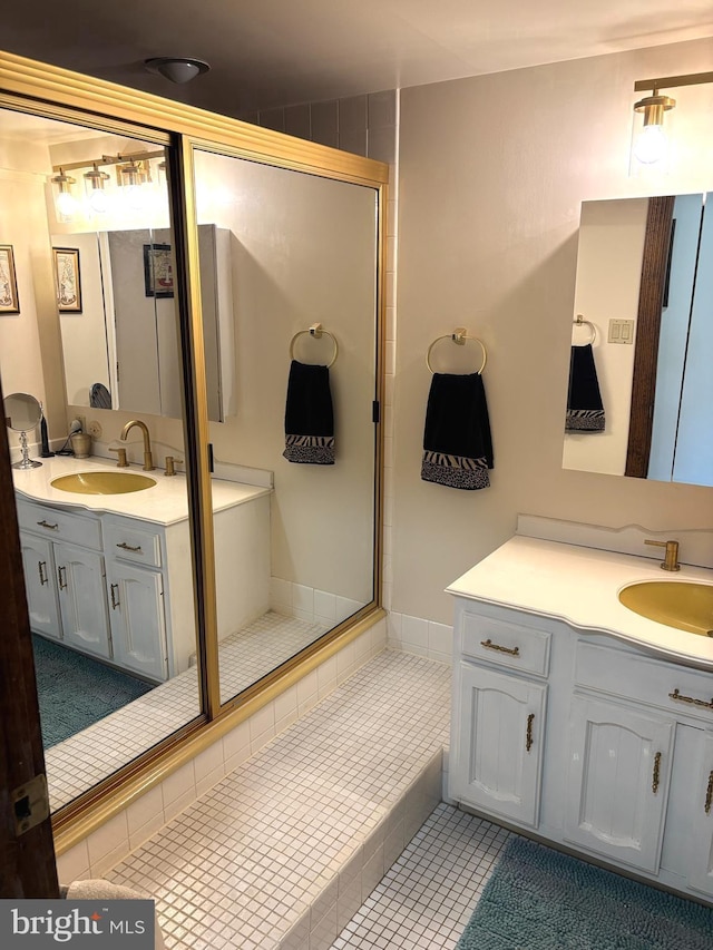 bathroom with a stall shower, tile patterned flooring, two vanities, and a sink