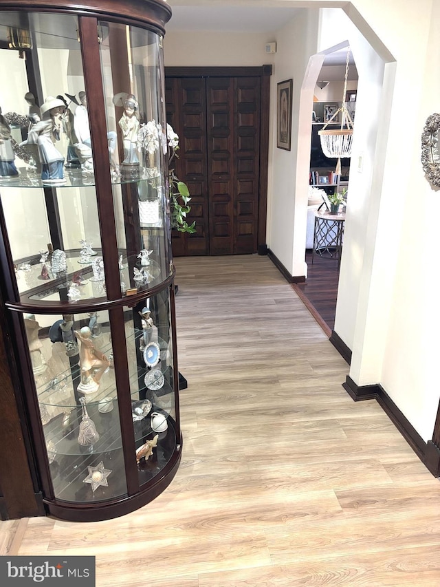 hallway featuring baseboards, arched walkways, and wood finished floors