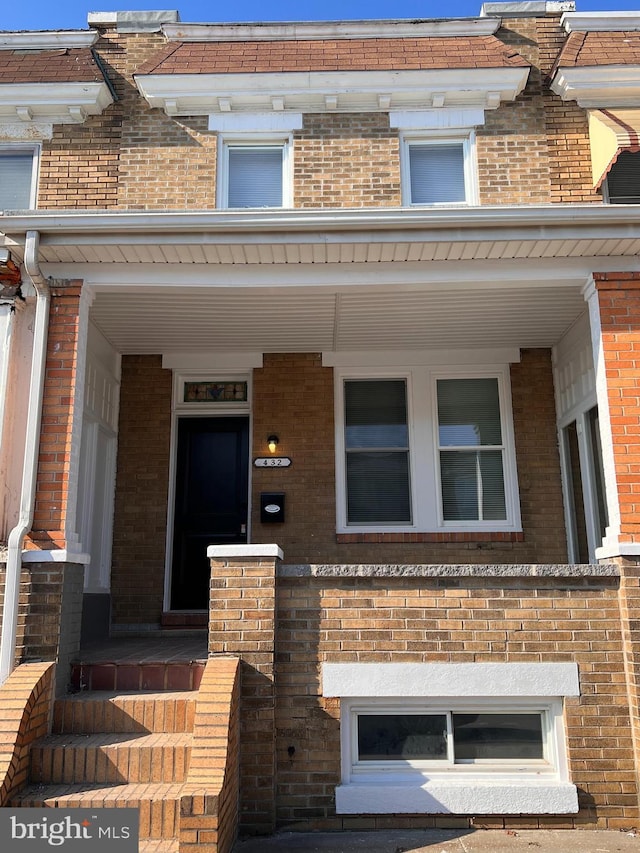 townhome / multi-family property featuring covered porch and brick siding