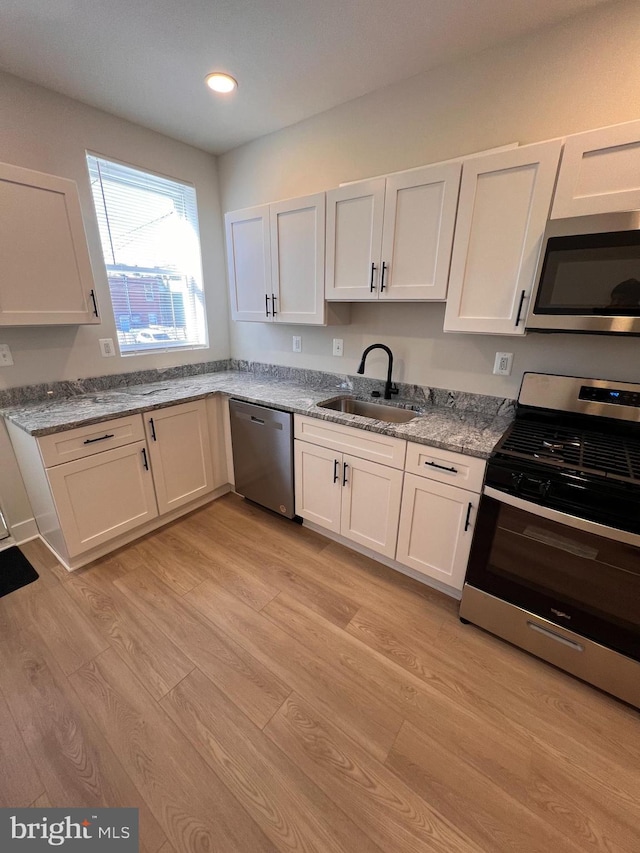 kitchen with white cabinets, stainless steel appliances, light wood-type flooring, a sink, and recessed lighting