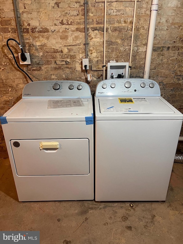 washroom featuring laundry area, independent washer and dryer, and brick wall