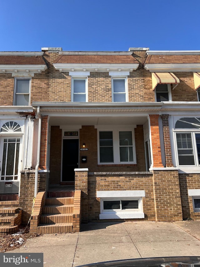 multi unit property featuring covered porch and brick siding