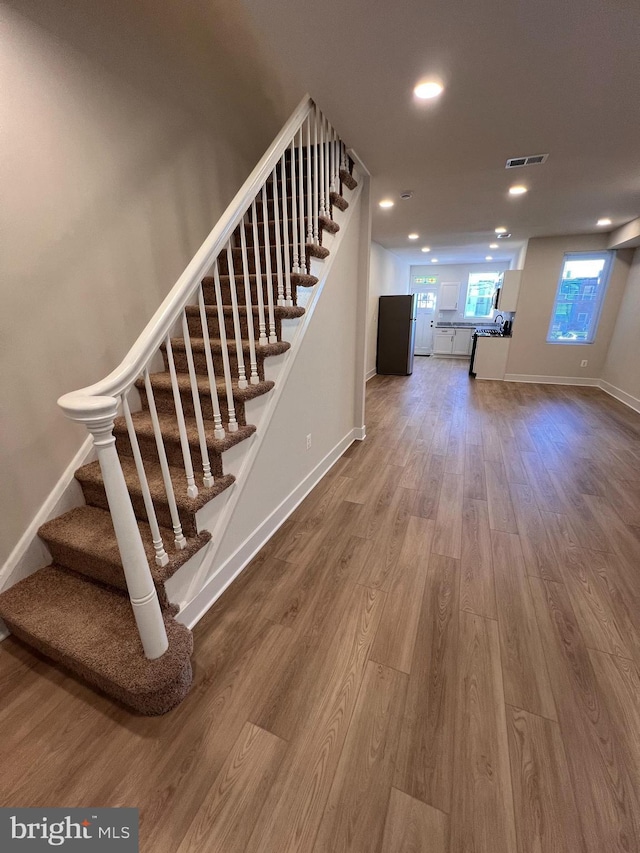 stairs featuring recessed lighting, visible vents, baseboards, and wood finished floors