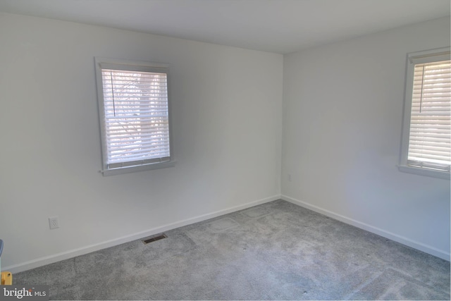 empty room with carpet flooring, visible vents, and baseboards