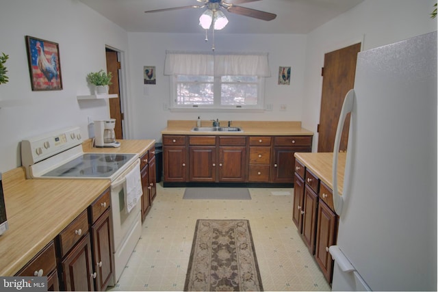 kitchen featuring white appliances, light countertops, a sink, and light floors