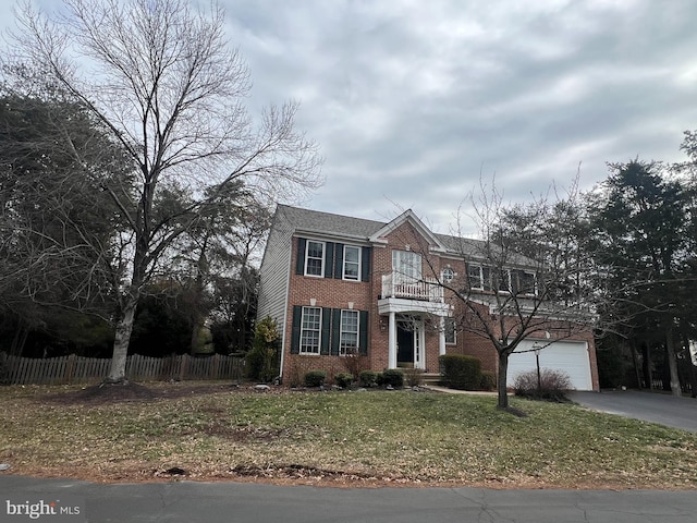 view of front of home featuring brick siding, fence, a balcony, a garage, and driveway