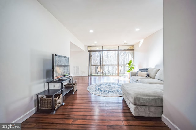 living room featuring floor to ceiling windows, visible vents, baseboards, and wood finished floors